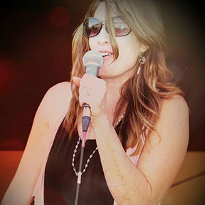Rachel Alena wearing sunglasses and holding a mic