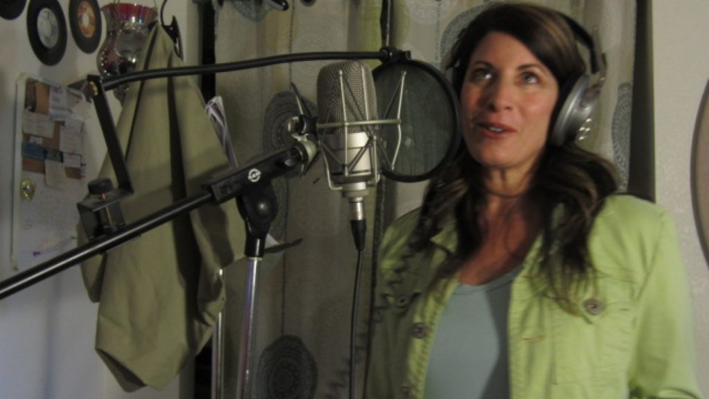 Rachel Alena wearing a green shirt standing in front of a microphone